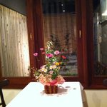 BISTRO TAKAGAKI - テーブル席から、綺麗な中庭（PATIO)が見えます。テーブルにもお花が飾られている。