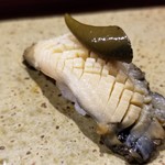 鮨匠 のむら - (21)焚き黒鮑(佐賀県唐津産)
      産卵期は秋～冬(禁漁)、旬は初夏～夏。
      6時間、大根の煮汁100%で焚き込んだ黒鮑は、大変柔らかく、その身がプルプルと震え、旨みも抜群です。