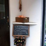 カロローゾ - 左側に、樽が置いてあり、その上にワインの空き瓶が置いてあります。 その上にボードが置いてありますね。 何て書いてあるんでしようね。