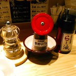 らー油肉つけうどんの南哲 - 卓上にはペッパーミル、黒く煎った白胡麻、辛くない通常の自家製らー油。あと一味もありました。
