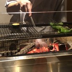 温石 - 炭火でズッキーニと松の舞獅子唐をじっくりと時間をかけて炙ります