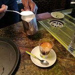 Café Daniel Moser - ガラス製のデミタスカップに慎重にコンデンスミルクを注ぎ、その上にマシーンで抽出したエスプレッソ、表面にはフォームミルクを