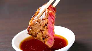 Aka Ushi Tare Yakiniku Marufuku - 肉をタレに付けている写真