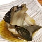 鮨匠 のむら - (11)焚き黒鮑(佐賀県唐津産)
      産卵期は秋～冬(禁漁)、旬は初夏～夏。
      禁漁期明けの黒鮑は6時間ほど大根の煮汁100%で炊き込んであり、大変柔らかく、その身がプルプルと震え、旨みも抜群です。