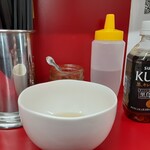 Ramen Jirou - 助手さんに促され店内へ。小豚と生玉子の食券をカウンター上に置くとまもなく生玉子がやってきました。生姜は買いませんでしたが、汁があるので....