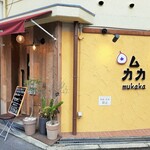 Mukaka - 黄色い壁に、三角形に配置された屋号の文字が可愛い特徴的な外観