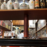 中山飯店 - 並べられた中国酒の間から見えた厨房
