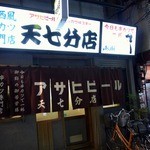 天七 - お店の外観です。 暖簾がいい感じですよね。 「今日も串カツで一杯　お勤めご苦労様」って書いていますよ。 何だか、ホッとする暖簾ですよね。