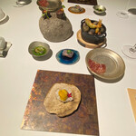 ラ・ヴァガボンド - 一口サイズのアミューズ～米粉のチップスの上にのる北海道産羽立水産の生うに、猪ベースのジビエソーセージ、アカザ海老に青海苔を混ぜ込んだベニエ、黒毛和牛の生ハム、シャリの代わりに茄子に金目鯛をのせた寿司、胡瓜のガスパチョ冷製スープに浮かぶ山口県産姫サザエ