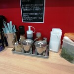 らーめん 尾又家 - にんにく、豆板醤、生姜の家系調味料３点セットの他には白胡麻、秘伝のたれ、酢、キュウリのキューちゃん的なものが卓上に。