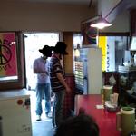 つけ麺 ボンズ - 店内はカウンターのみの構成で、後ろに待合席が並ぶ。