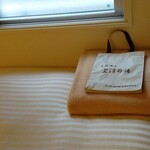 スーパーホテル - ベッドの上の毛布と大浴場用のバッグ