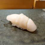 伊勢鮨 - 根室・ほたて（￥495）。久米島の塩を振り掛けて、素材の甘みを引き出す