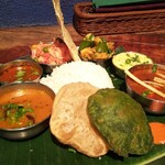 手前の2色のプーリー、カレーの皿の下にはバナナの葉が敷かれてカラフルな装い