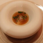 エヴォリュエ - 最後のお料理は目の前でスープを注いで下さる演出！七谷鴨と九条ネギ、蓮根のラビオリ、生姜風味のコンソメを注いで