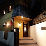 エヴォリュエ - 福島の静かな路地で柔らかなランプの光が照らし出す、黄色の壁が映える一軒屋レストラン