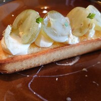 Bistro Sifflet - デザート:シャインマスカットとクリームチーズのタルト。あったかいタルトに冷たいマスカット！蕩けていくクリームチーズ！砕いたマカロン(よもぎ)も散りばめられて見た目以上に絶品でした♡
