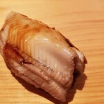 鮨 さかい - (23)煮真穴子(長崎県対馬列島産)
      産卵期は初夏～初秋、旬は夏～秋
      ふわふわと軟らかい煮穴子、温かいシャリ
      口の中に入れた瞬間にシャリがほどけます
      一気に拡がる旨み、ツメも濃過ぎず軽やかな後味です