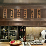 とり茶太郎 - 焼き台奥のスペースには野菜や酒が所狭しと置いてあり、上には扱っている肉の銘柄が掲げられています