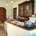 ルーラル・カフェ - 明るいオープンキッチン、重厚な食器棚が白壁に存在感バッチリ