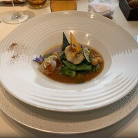 ナベノ-イズム - アオリイカとカサゴのソッカフライ、夏野菜（つるむらさき、ズッキーニ、ミニオクラ）と共にフランス国民食「クスクス」仕立てに、ミントとコリアンダーを香らせ、薫り高いブイヨンを注いで