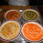 PANAS - カレー(スモールサイズ)4種:ミックスシーフードカレー(手前左)、バダーブラウン(エビカレー)(手前右)、サグパニール(カッテージチーズ入りほうれん草カレー)(後方右)、ポークカレー(後方左)