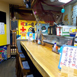 Mangetsu - 渋いカウンター席の奥に、漁網と大漁旗が掲げられる
