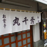 丸千葉 - お守りのようにはためく暖簾。