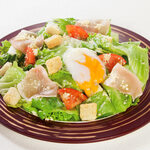 Raw Prosciutto Caesar salad topped with warm egg