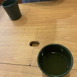 Muten Kurazushi - 2021/08 テーブルは穴付きテーブル。テーブルの真ん中にカバーされた穴があり、今までの[a:rstlst,無添くら寿司]の店舗ではテーブルに置かれていた箸やスプーン、醤油やガリなどがその穴の中に置かれている。なんか、お茶などテーブルにこぼしてしまったら、大変なことになるような気がする。大丈夫？？？？