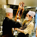 仁修樓 - ◎上岡シェフとお弟子さんが、子豚に金具を入れていく。