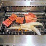 焼肉ライク - トングで肉を掴みロースターの上にジュー