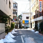 しま坂 - 商店街直進し、クリーニング屋さんを左折した後の風景。先に見える突き当りを右へ行くと右手にお店