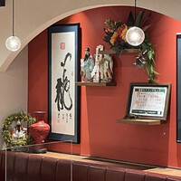 四川料理 龍の子 - 「一龍」が龍の如く飛び跳ねている感じの書とか何やら中国感溢れる壁紙の赤とオブジェ達。