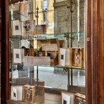 Caffè Bruno - サヴォイア家の公式紋章 Pietro Bruno Confettiere Liquorista が掲げられた下のショウケースにグラッパが並んでいた