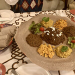 クイーンシーバ エチオピアレストラン - インジェラ(大きな灰色のクレープ)に、
            メニューから選んだ3種のシチュー、インクラル(スクランブルエッグ)がのって、提供されます。