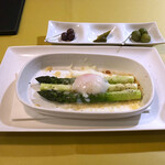 オステリア・ろじえ - 新潟産アスパラガスのパルメザンチーズ焼き温泉卵のせ880円。新鮮で柔らかいアスパラは甘く、チーズの酸味、卵の旨味と相まって、白ワインのおつまみに最高