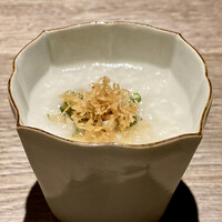 一平飯店 - シジミのお出汁で炊いたお粥
                    温かなお粥を最初にいただくと、胃が温まると共に落ち着きます♪
                    上にはつぶ貝と葱に干し貝柱を揚げたものを乗せ、食感のアクセントとあっさりとしたお粥に味わいをプラスしています。