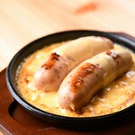 Giant sausage topped with cheese on an iron plate