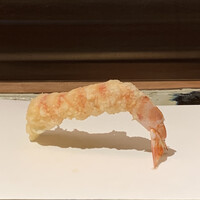 天ぷら 元吉 - まずは、代名詞とも言えるブリッジ型の巻き海老。
                    薄衣と塩で、海老自体の味わいをしっかりと。
