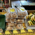 八重岳ベーカリー - ザルに並べられたパンの反対側に積みあがったパンからクルミパンをチョイス。隣には島バナナが売ってました。