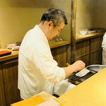 富小路 やま岸 - ◎鱧を炭火で炙っていく。店内は煙が立ち込める。