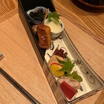 もちづき - 金時草、とうもろこし、バイ貝、粟麩の照焼き、タコの柔らか煮、いぶりがっこ、チーズ豆腐の味噌漬け、枝豆、落花生、赤蒟蒻