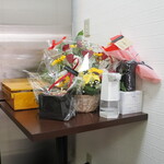 ラーメン 三亀 - 隅に置いてある開店祝いと思しきお花。後ろに菅野製麺の期の麺箱が置いてある。菅野はふつうはプラの麺箱を使っているみたいですけど