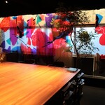 PENITENT - 舞台のような巨大なテーブルと、赤やピンクの光を通した幻想的な壁。