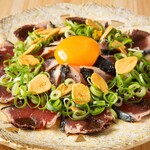 Seared bonito covered in green onions and topped with yolk