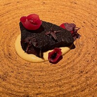ライラ - かつお 　燻製された鰹に墨状のパウダーをつけたもの。 　下には秋茄子のソース、シチリアのアーモンドを添えて。 　鰹の生臭さは見事に消えてほんのりと感じる赤身の濃厚さが軽めの日本の赤ワインに合う。