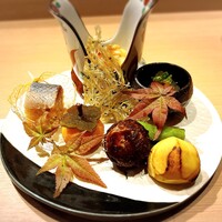 難波 鮨 よこ田 - 前菜8種（上から右回りに胡麻豆腐の木の身餡かけ、くらげポン酢、静岡のだだちゃ豆、焼栗、きぬかづき、柿に見立てた卵黄の醤油漬け（上に昆布と牛蒡）、北海道の新さんまの小袖寿司、畳鰯）