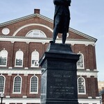 Sam Adams Boston Taproom - サミュエル・アダムスの銅像。後ろがファニュエルホール中核施設の一つ、1742年に建てられた The Great Hall です。