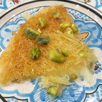 アラブ料理専門店 七つの丘 SEVEN HILLS - クナーフェ "Kunafeh"「アラブ世界で広く食べられている人気のスイーツ。小麦粉の生地にチーズを挟んで焼き、ナッツを振りかけていただくあたたかいデザート」※メニュー表記通り